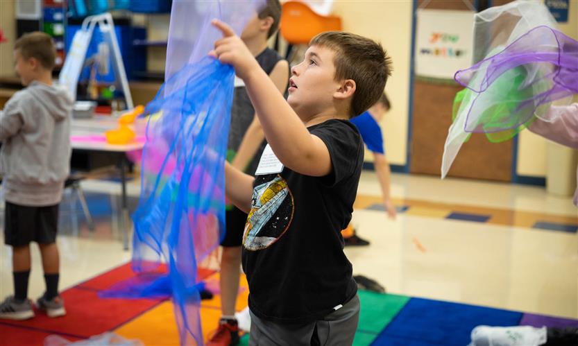 A boy in a black shirt juggles scarves